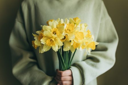 The woman holds a bouquet of yellow daffodils